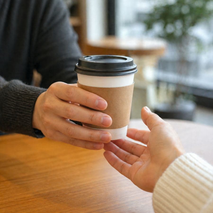 A hand passing a cup of coffee